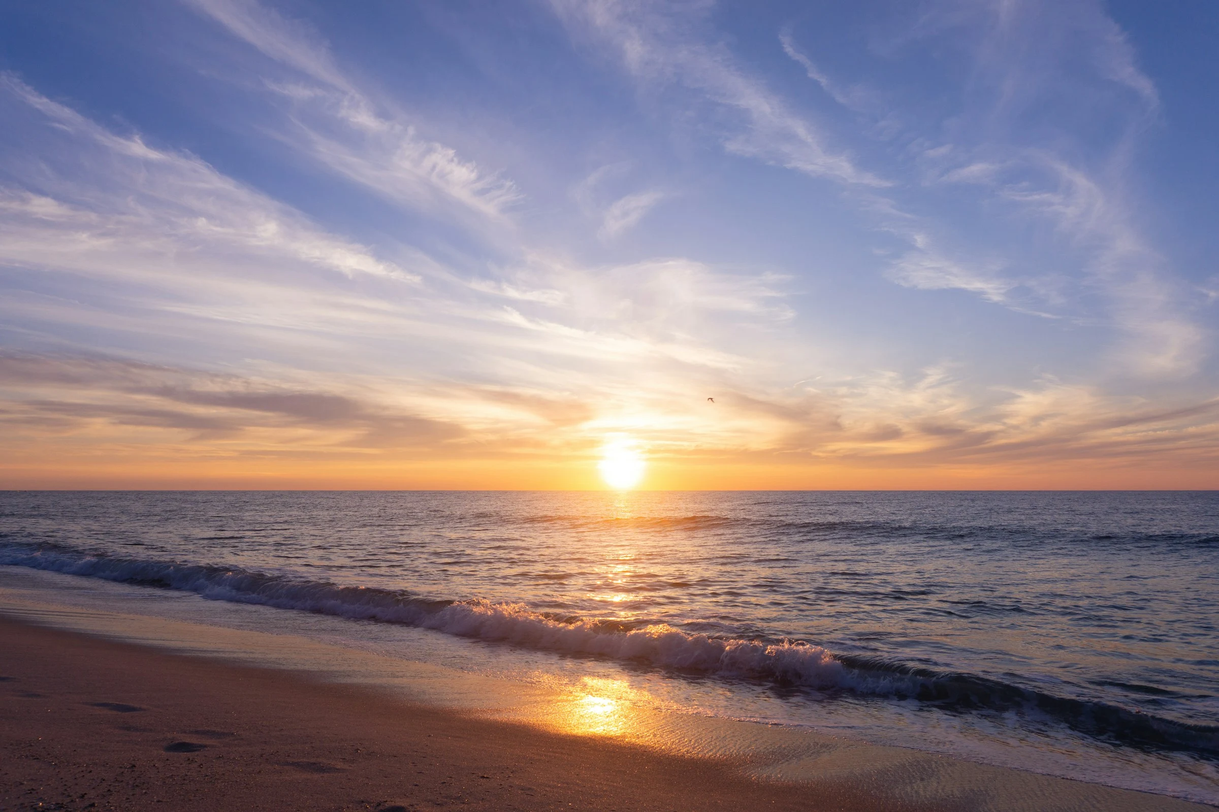 Golden light over gentle ocean waves and a sandy beach
